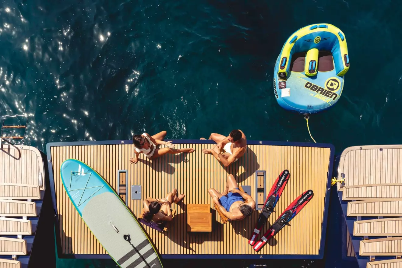 Happy people socialize and enjoy the view from the expansive aft platform of a Sunreef 80 luxury catamaran.