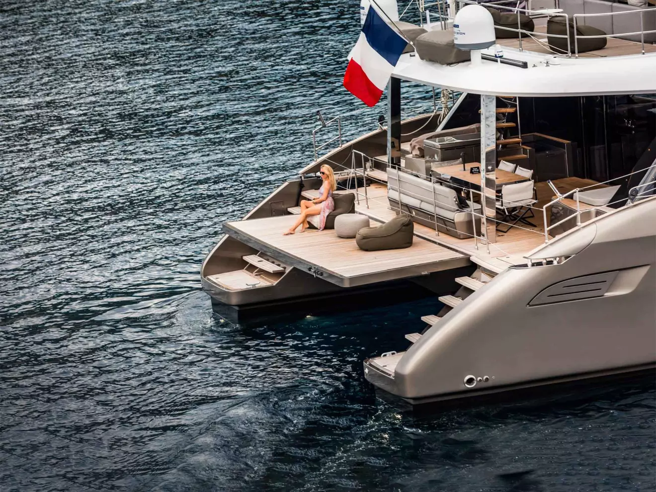 he expansive aft platform of a Sunreef 70 catamaran, with a woman enjoying the space.