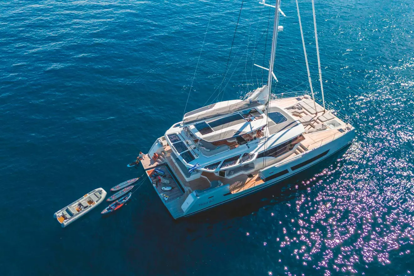 A Fountaine Pajot Thira 80 catamaran peacefully at anchor, reflecting the serenity of a sailing vacation.