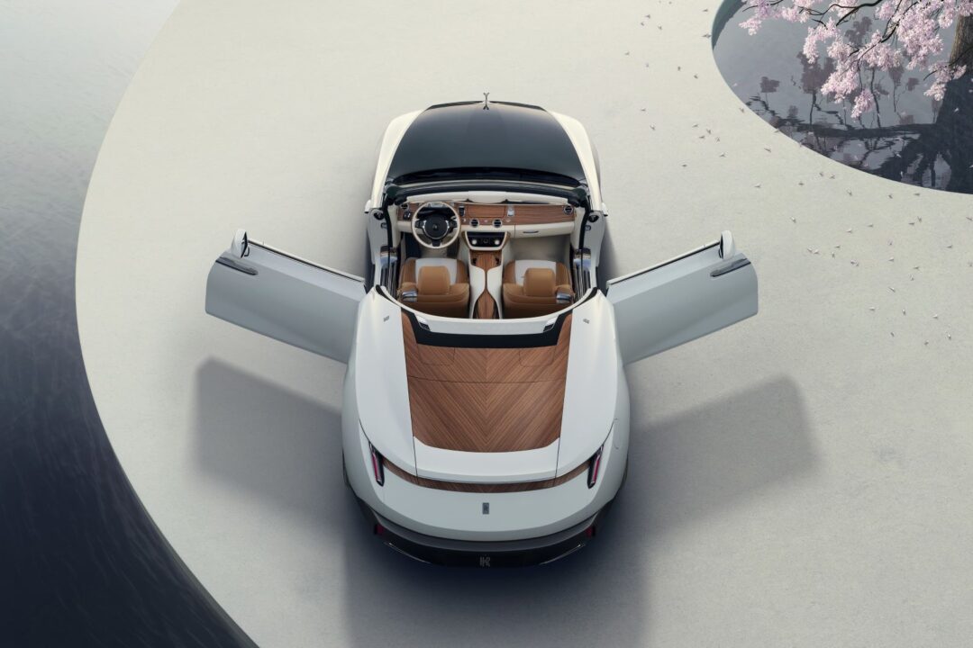Overhead shot of a white Rolls-Royce Arcadia Droptail, one of the cars inspired by yachts, with a wooden rear deck and open coach doors.